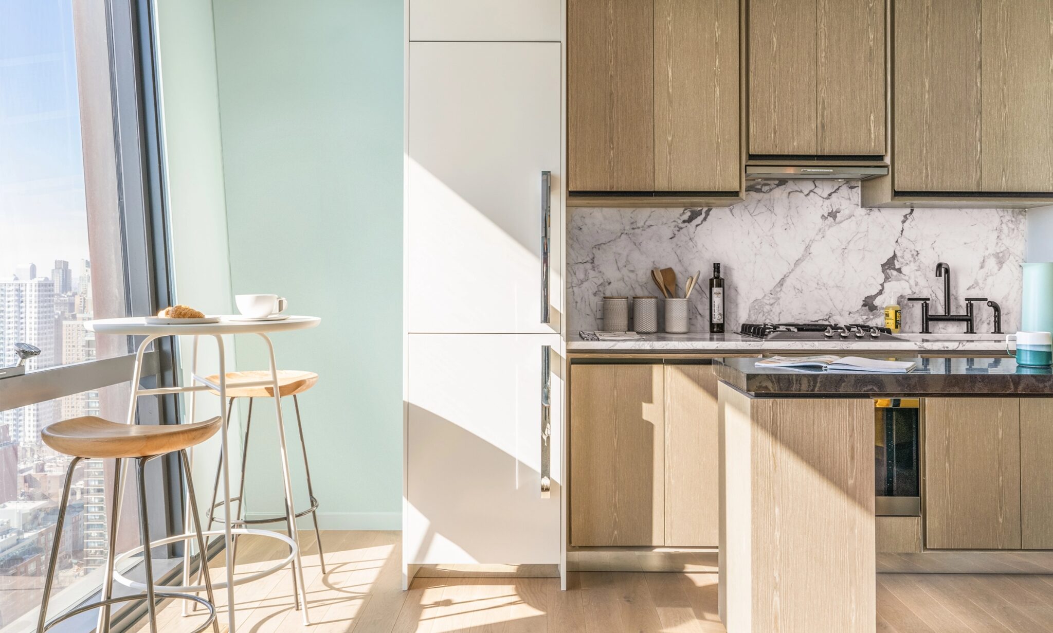 Modern kitchen at The Copper in Murray Hill, boasting an open layout, elegant white marble backsplash and a luxurious island.