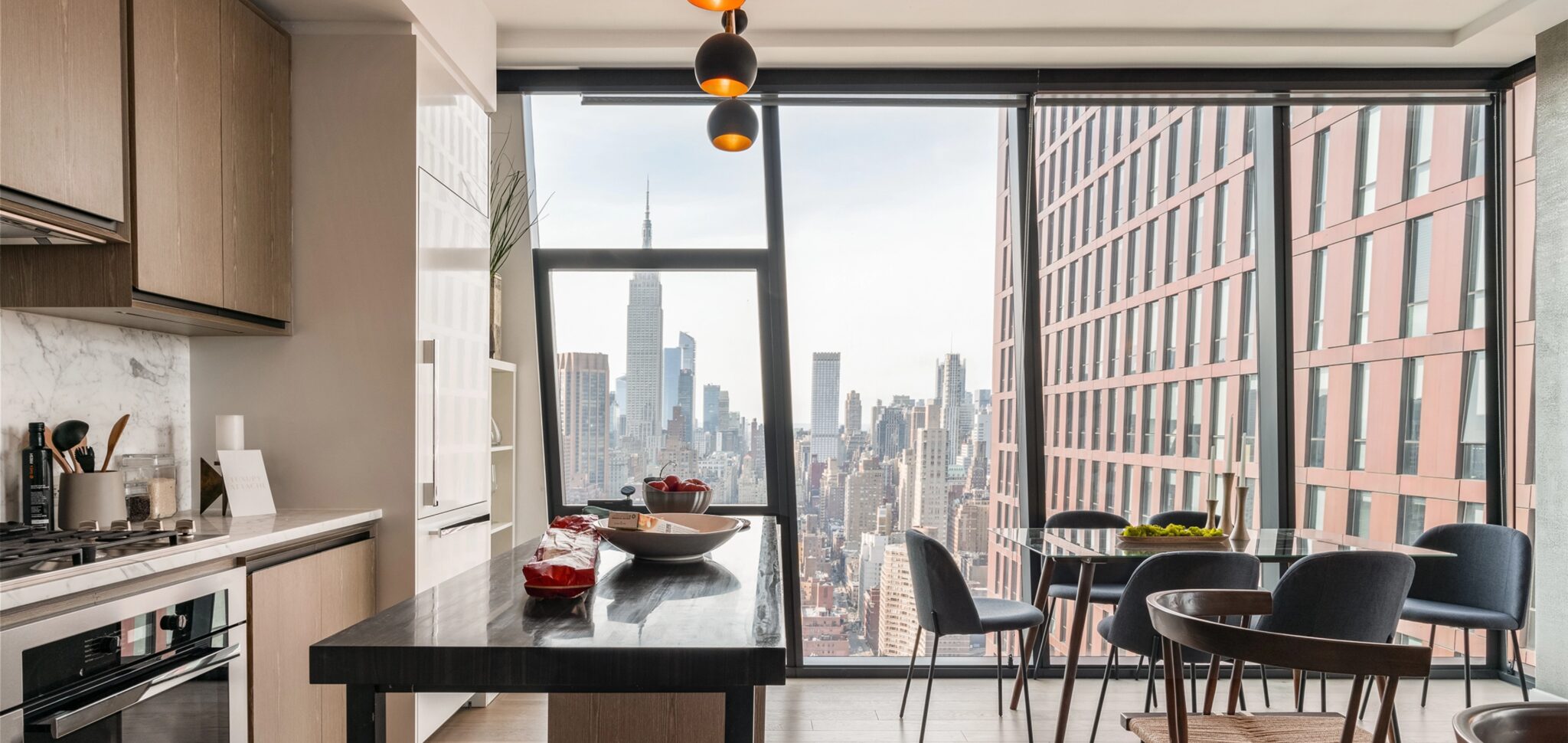 Luxury kitchen at The Copper apartments for rent in Murray Hill featuring dining table and stunning Manhattan skyline views.