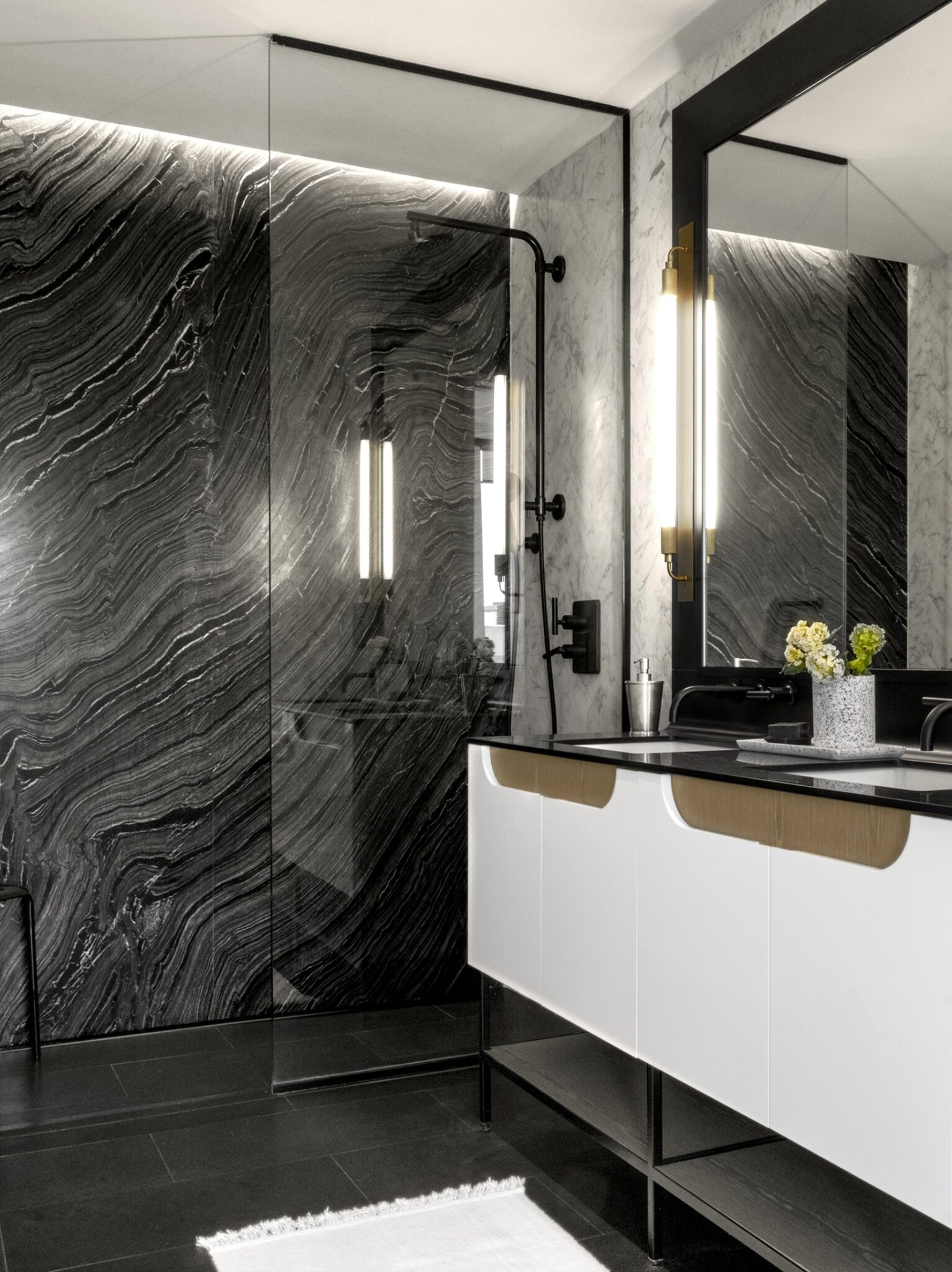 Stunning modern bathroom at The Copper apartments in Murray Hill featuring a marble wall, double sinks, and a rain shower.