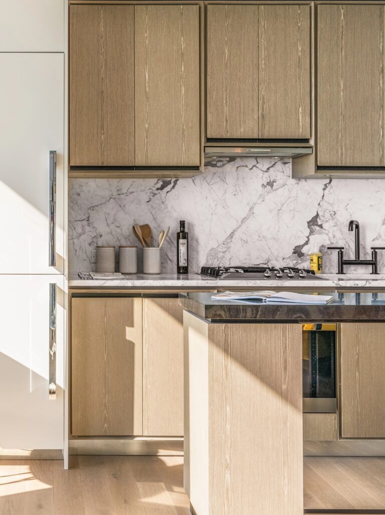 Modern kitchen at The Copper in Murray Hill, featuring a spacious island and beautiful marble backsplash for luxury living.