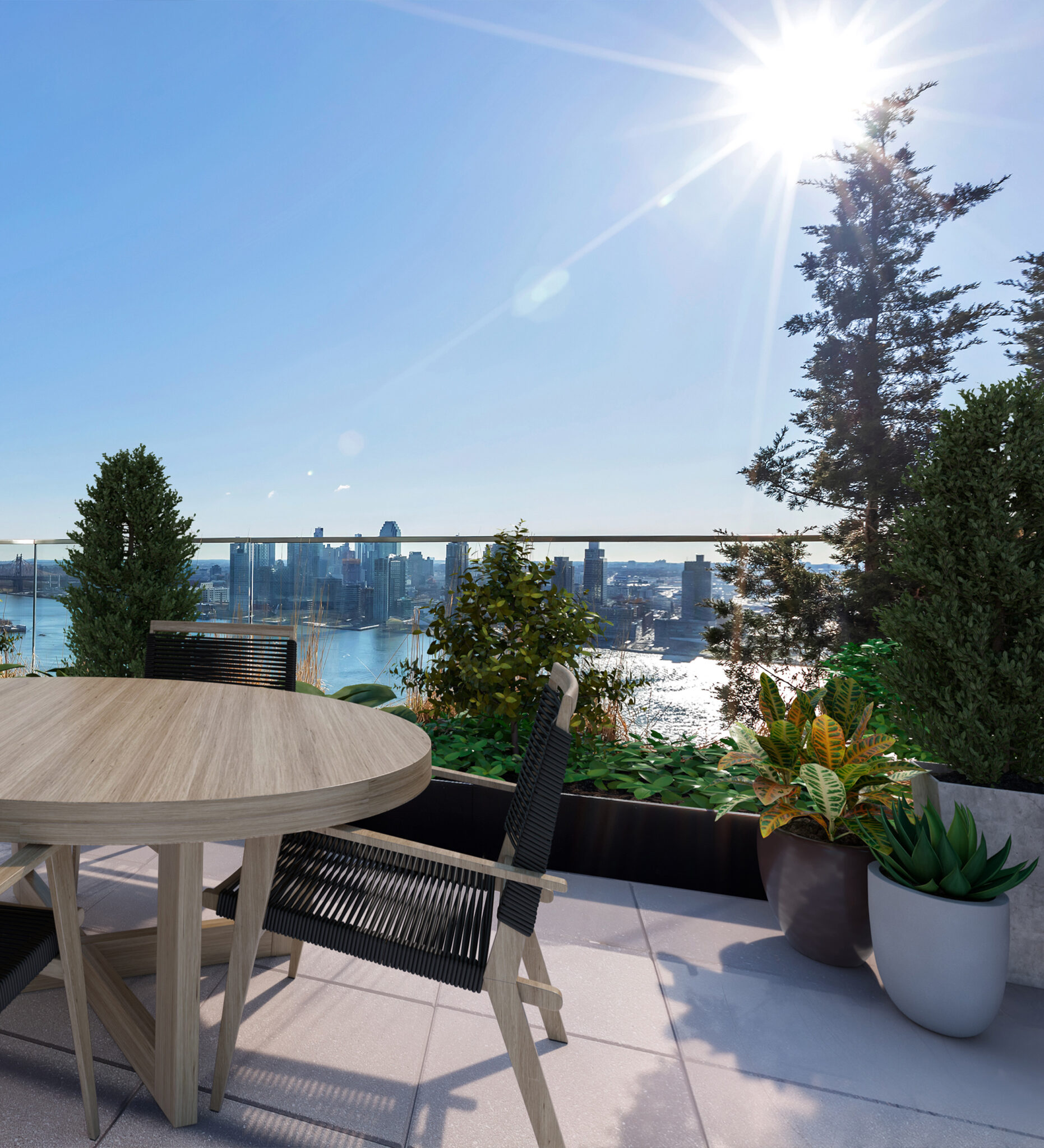 Private outdoor terrace at The Copper apartments in Murray Hill, with greenery, comfortable seating & East River views.