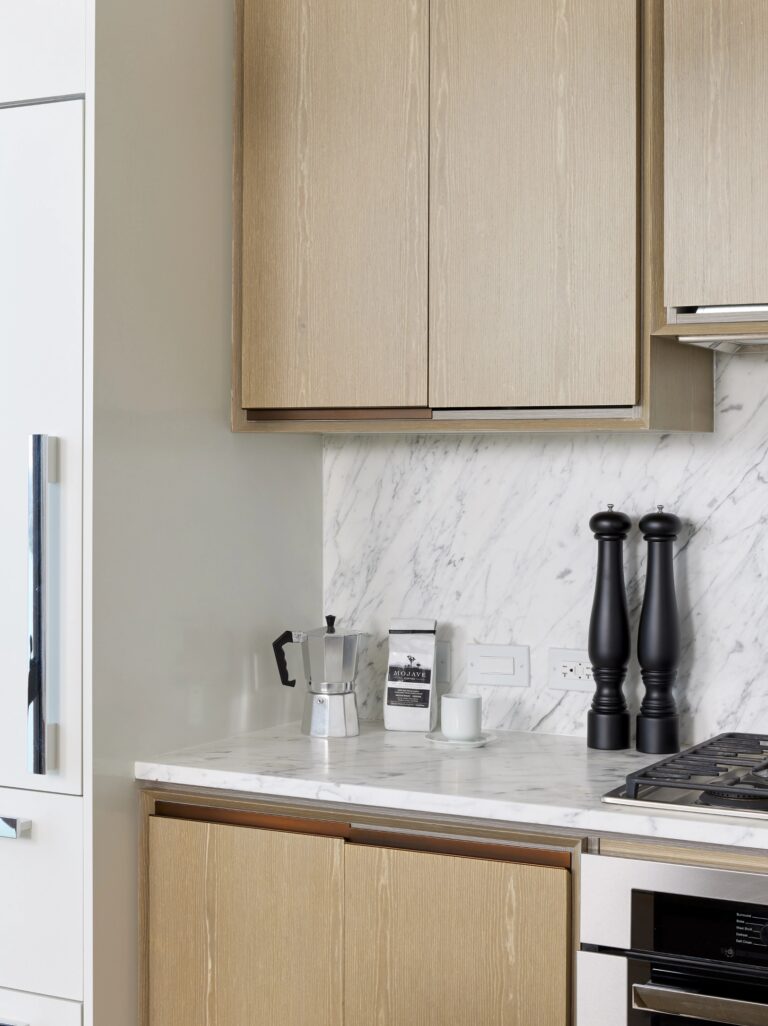 Modern kitchen at The Copper in Murray Hill, featuring sleek white marble surfaces and ample storage space.