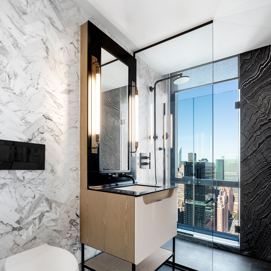 Gorgeous bathroom at The Copper apartments in Murray Hill featuring a white backsplash, rain shower, and stunning city views.